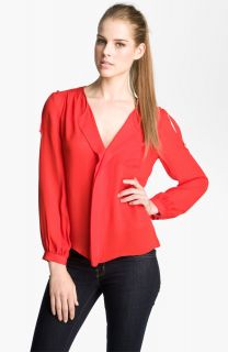 Extended epaulettes contrast the soft styling of a silk blouse framed 